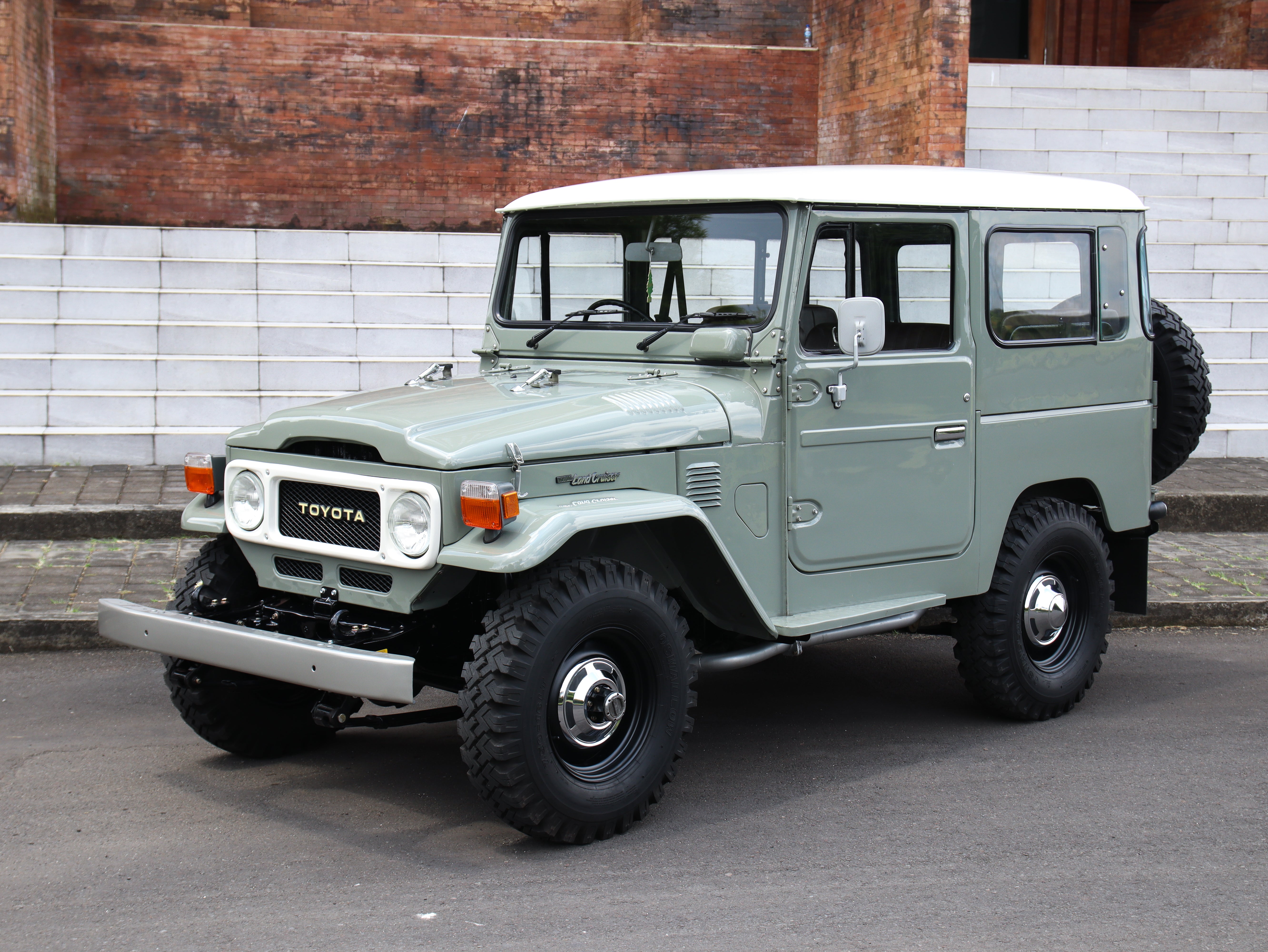 Vintage Toyota Land Cruiser parked on a street with a brick building in the background