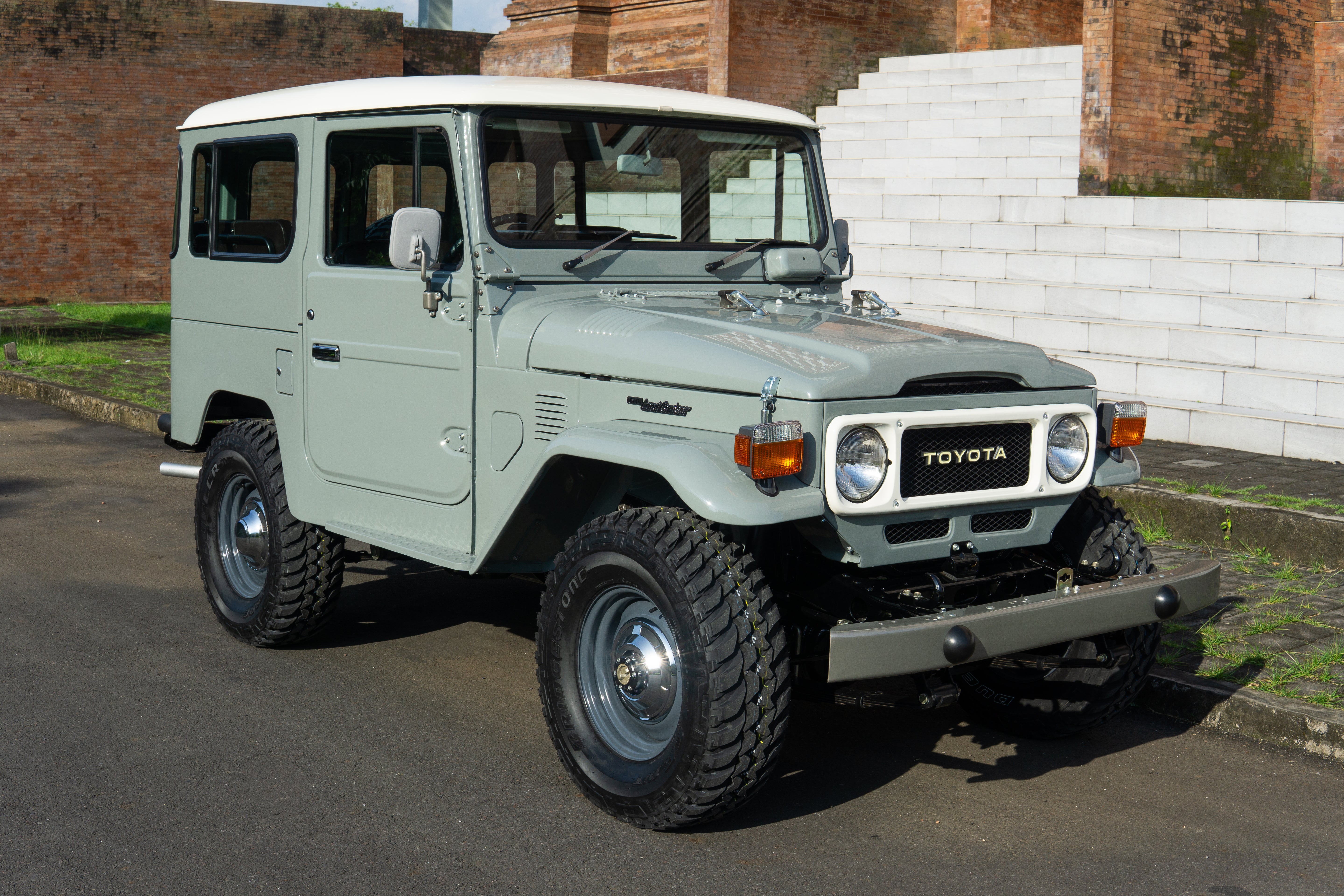 Light green Toyota Land Cruiser parked on a street with classical architecture in the background