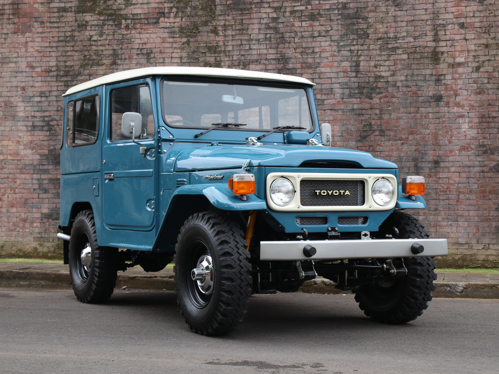 Restored FJ40 Land Cruiser for sale outside classic car showroom
