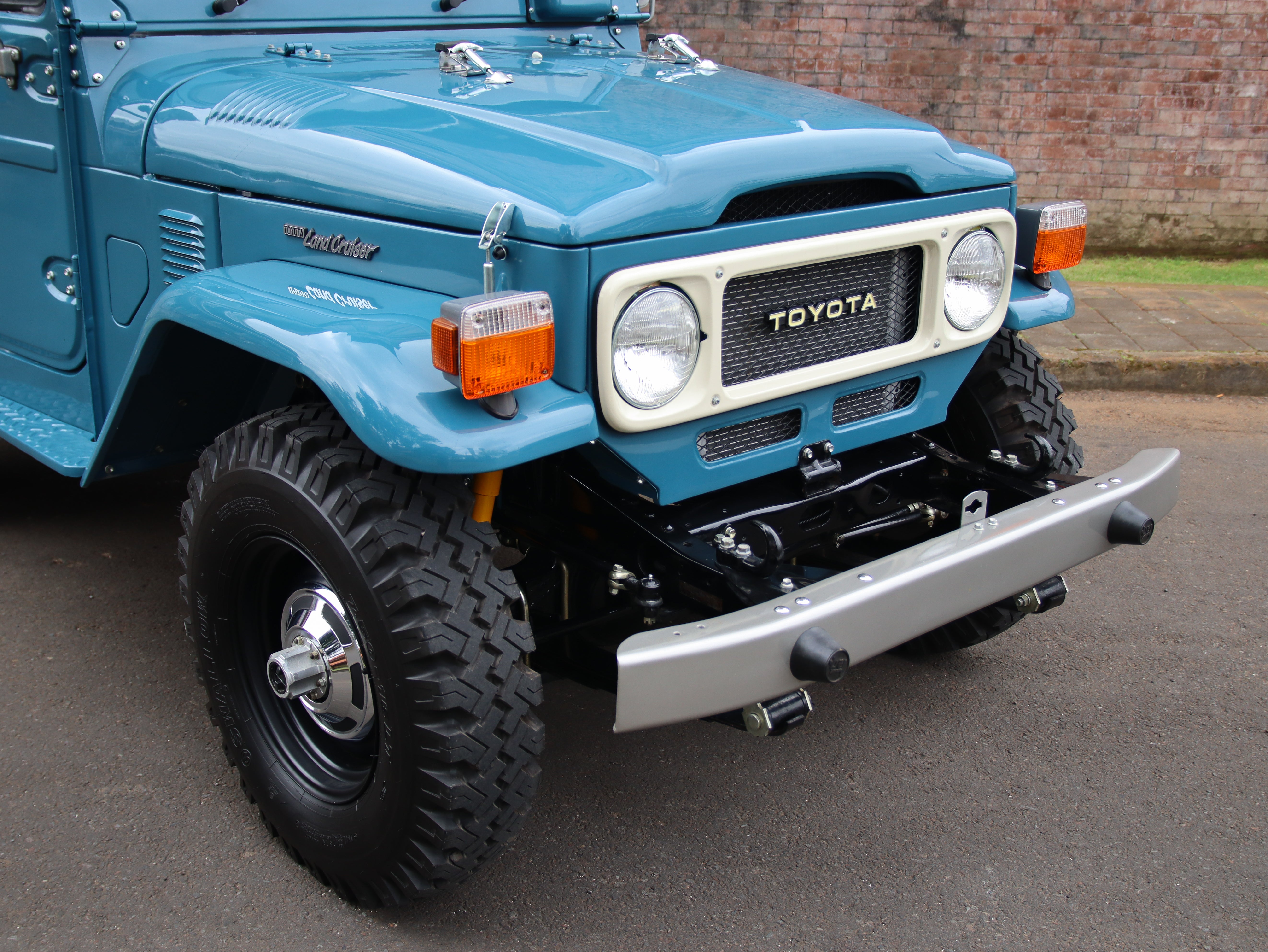 Blue Toyota Land Cruiser parked on a street with a brick building in the background